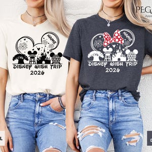 May include: Two t-shirts, one natural and one heather dark grey, featuring a Disney-themed graphic. The design includes Mickey Mouse ears, a castle, fireworks, and the text "Disney Wish Trip 2026". The natural shirt has a black graphic, while the dark grey shirt has a white and red graphic.
