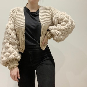 Bubble Sleeve chunky knit cropped cardigan. uses 12mm and 15mm needles to achieve chunky over sized look. the sleeves are made up of a 1x1 rib knit cuff and bubble stitch bubble sleeve. the body is made up of half knit stitch and half stocking stitch