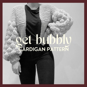 Könnte beinhalten: Ein Schwarzweißfoto einer Person, die einen grauen Strickcardigan mit großen, bauschigen Ärmeln trägt. Der Cardigan ist kurz und hat einen V-Ausschnitt. Der Text "get bubbly CARDIGAN PATTERN" ist unterhalb der Taille der Person gedruckt.