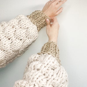 close up image of the sleeve. this chunky knitted cardigan sleeve is made using the bubble stitch and 1x1 rib stitch