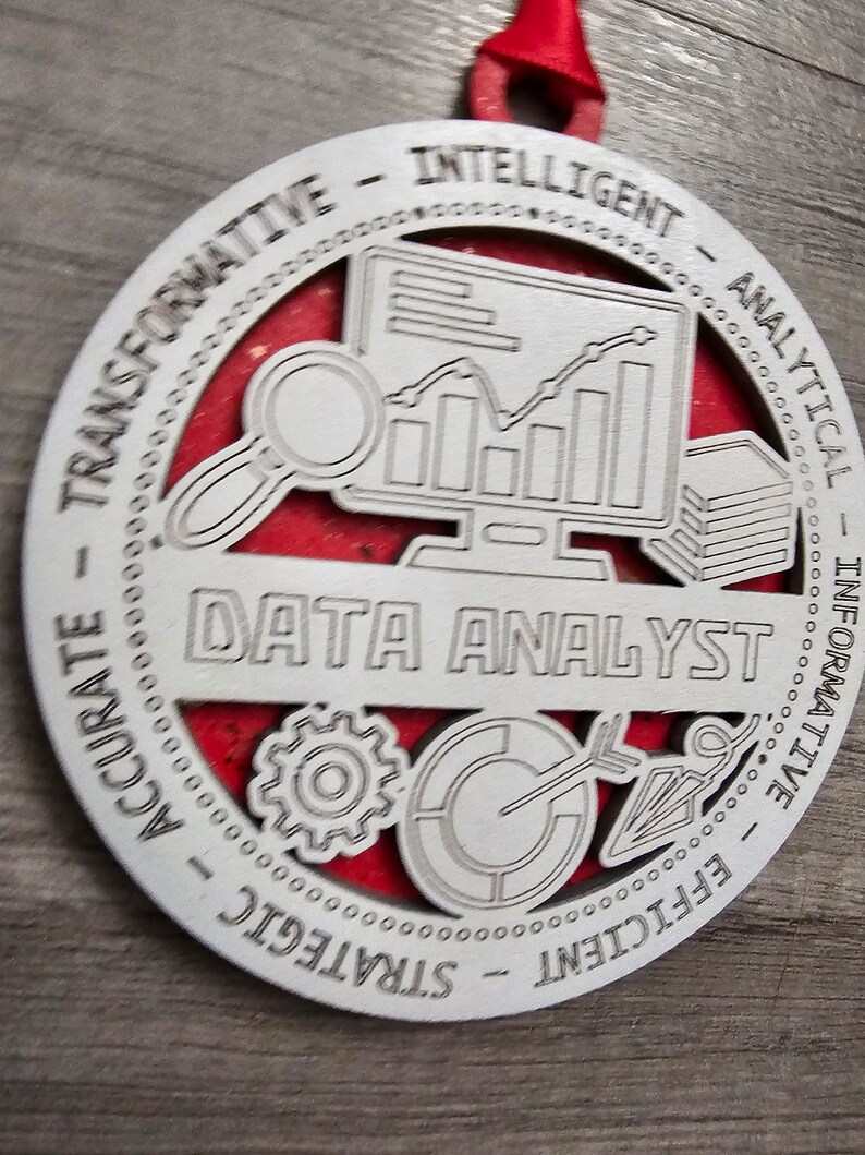 May include: A circular ornament with a silver-toned front layer featuring the text DATA ANALYST and icons of a computer monitor, magnifying glass, gear, and target. The words TRANSFORMATIVE, INTELLIGENT, ANALYTICAL, INFORMATIVE, EFFICIENT, STRATEGIC, and ACCURATE are engraved around the border, set against a red background.