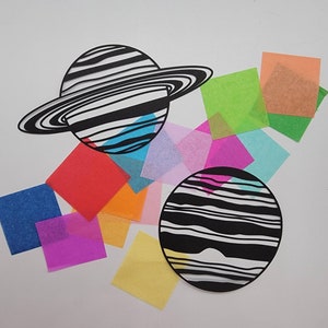 May include: Black and white paper cutouts of two planets, one with rings, on a white background.  Surrounding the planets are colorful tissue paper squares in various shades of blue, green, red, pink, yellow, and orange.