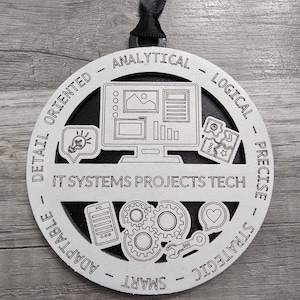 May include: A white wooden circle with black text and icons. The text reads "IT SYSTEMS PROJECTS TECH" and the icons represent skills such as analytical, logical, precise, strategic, smart, adaptable, and detail oriented.