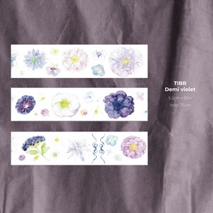 May include: Three strips of washi tape with a floral design featuring purple, white, and blue flowers. The tape is labeled "TIBR Demi violet 5.2cm x 10m loop: 7.5cm"
