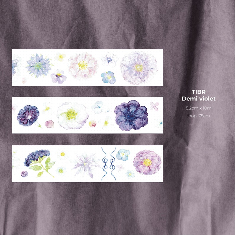 May include: Three strips of washi tape with a floral design featuring purple, white, and blue flowers. The tape is labeled "TIBR Demi violet 5.2cm x 10m loop: 7.5cm"