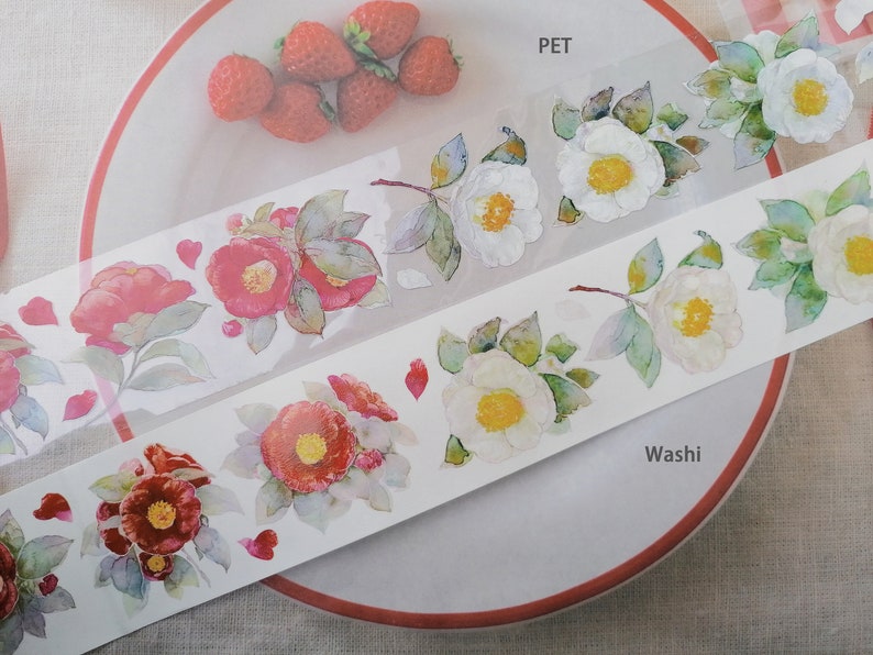 May include: Two rolls of decorative tape with floral designs. One roll is labeled "PET" and features white flowers with green leaves. The other roll is labeled "Washi" and features red flowers with green leaves.