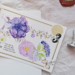 May include: A white card with gold trim features watercolor illustrations of flowers and stars. The card has the text "Girl's courage" and a quote about hope and faith.