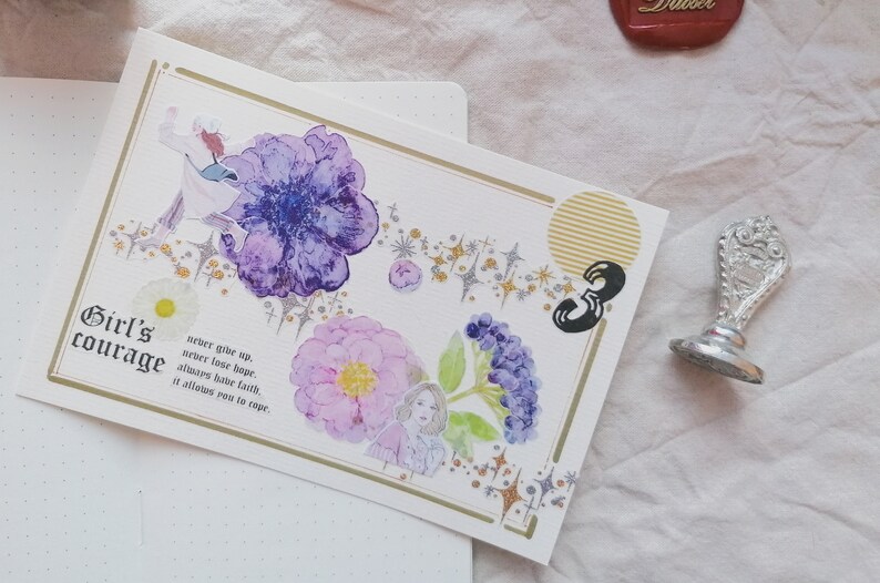 May include: A white card with gold trim features watercolor illustrations of flowers and stars. The card has the text "Girl's courage" and a quote about hope and faith.