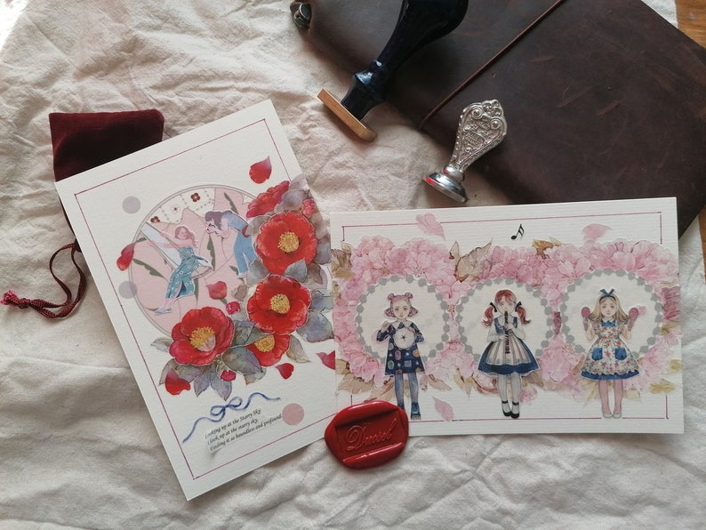 May include: Two cards with watercolor illustrations. The first card features a pink and blue illustration of a woman with wings flying in a circle of flowers. The second card features three women in dresses with floral accents. The text on the first card reads "Waking up as the dawn breaks, I look up at the morning sky, Feeling as beautiful and profound as the flowers in my garden."