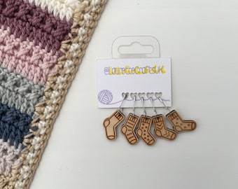 May include: Set of six wooden sock stitch markers with different designs. The markers are attached to silver rings. The card they are on says "@LauretteCraftsUK".
