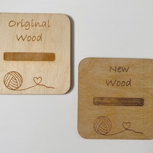 May include: Two wooden signs with the text "Original Wood" and "New Wood" engraved on them. Each sign has a slot for a yarn ball and a small heart design.