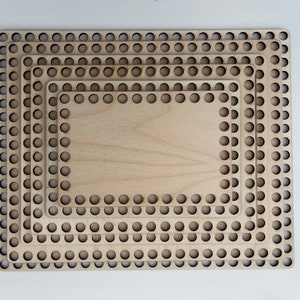 May include: Four unfinished wooden basket bases stacked together. Each base is rectangular with rounded corners and a series of holes around the edge. The wood has a light, natural colour.