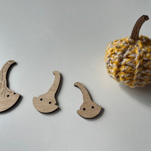 May include: Four wooden pumpkin pieces in various sizes, with a crocheted yellow and white pumpkin in the background.