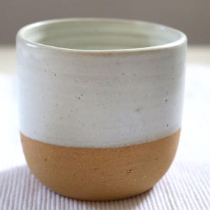 minimalistischer Keramikbecher aus lederfarbenen Ton mit weißer Glasur, gerade Form, henkellos, Steinzeugkeramik von der Töpferscheibe
