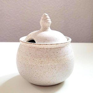 Azucarero, bulboso y beige. Hecho en el torno del taller de cerámica. Recorte en la tapa para una cuchara. Hecho a mano.