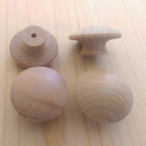 May include: Four wooden knobs with a round shape and a small hole in the center. The knobs are light brown in color and have a smooth finish. Five silver screws are also included.