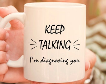 May include: White ceramic mug with black text that reads "KEEP TALKING I'm diagnosing you".