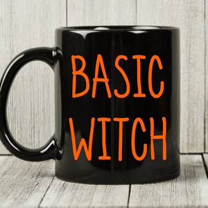 May include: Black coffee mug with the text "BASIC WITCH" in orange lettering.