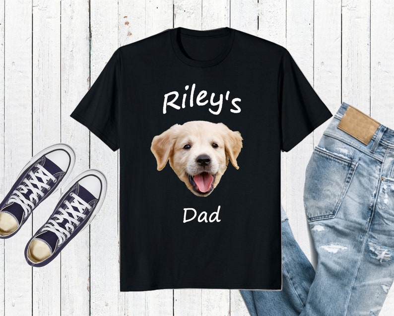 May include: Black t-shirt with a white graphic of a golden retriever puppy. The text "Riley's Dad" is printed below the puppy.
