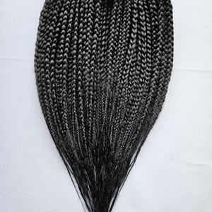 May include: A bundle of black pre-braided hair extensions. The hair is in a long, straight style and is ready to be used for braiding.
