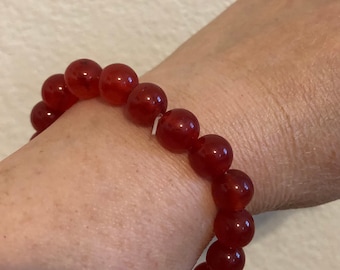 May include: A red gemstone bracelet with round beads.