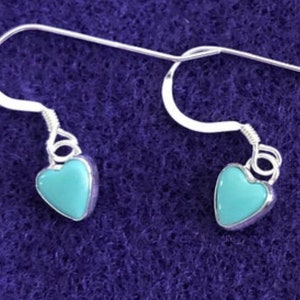 May include: A pair of silver heart-shaped earrings with turquoise blue stones.