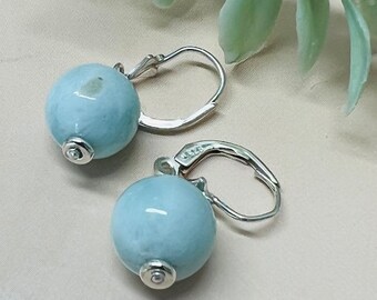 May include: A pair of silver earrings with light blue round gemstone drops.