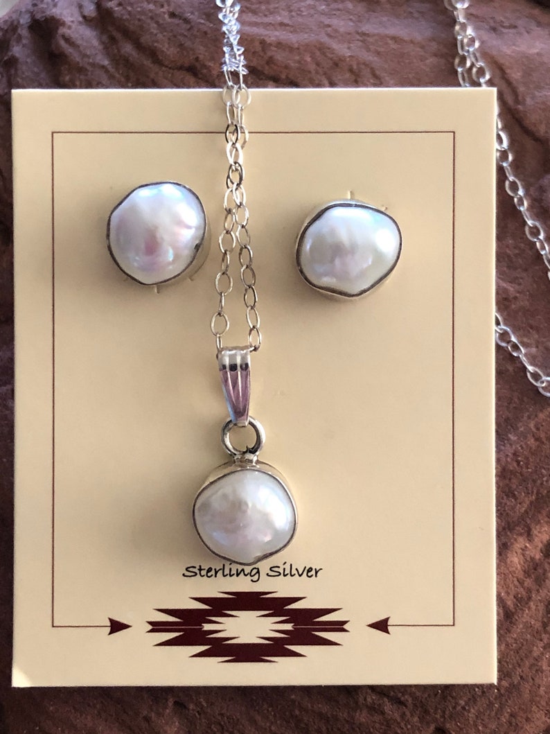 May include: A set of pearl earrings and a pearl necklace with a sterling silver chain. The pearls are white and have an iridescent sheen. The necklace and earrings are displayed on a brown card with the text "Sterling Silver".