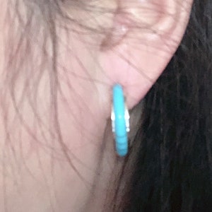 May include: A pair of turquoise hoop earrings with a silver finish.