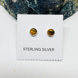 May include: A pair of sterling silver stud earrings with round tiger's eye gemstones. STERLING SILVER is printed on the card.
