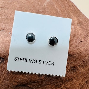 May include: A pair of black stud earrings on a white card with the text "STERLING SILVER".