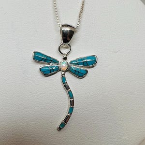 May include: A silver necklace with a turquoise and opal dragonfly pendant.