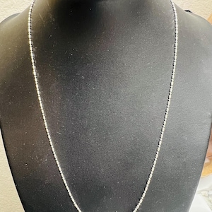 May include: A silver chain necklace with a delicate, round bead design.