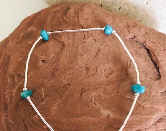 May include: A silver chain bracelet with turquoise beads. The bracelet has a magnetic clasp.