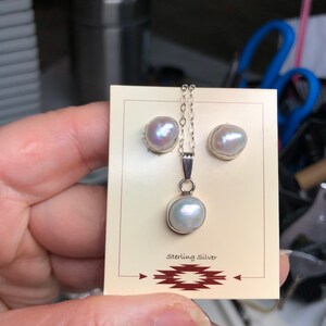 May include: A set of pearl earrings and a pearl pendant necklace. The jewelry is made of sterling silver and features white pearls. The jewelry is displayed on a card with the words "Sterling Silver" printed on it.