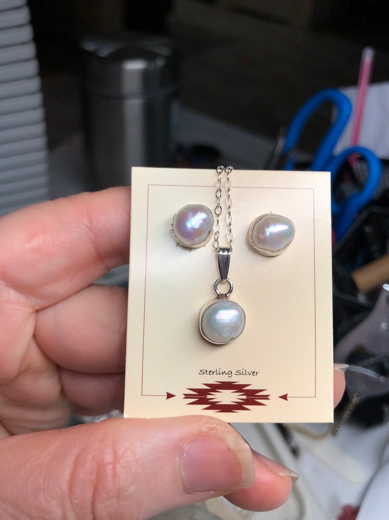 May include: A set of pearl earrings and a pearl pendant necklace. The jewelry is made of sterling silver and features white pearls. The jewelry is displayed on a card with the words "Sterling Silver" printed on it.