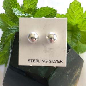 May include: A pair of sterling silver stud earrings on a white card with the text "STERLING SILVER".