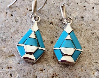 May include: A pair of silver dangle earrings with turquoise inlay. The turquoise is a light blue color and is set in a geometric pattern. The earrings have a hook closure.