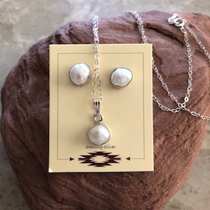 May include: A white pearl necklace and earrings set with sterling silver chain and posts. The pearls are irregular in shape and have a natural, organic look.