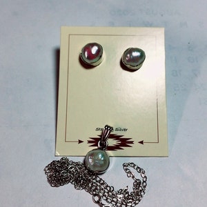 May include: A set of pearl earrings and a pearl pendant necklace with a sterling silver chain. The earrings and pendant are on a white card with the words "Sterling Silver" printed on it.