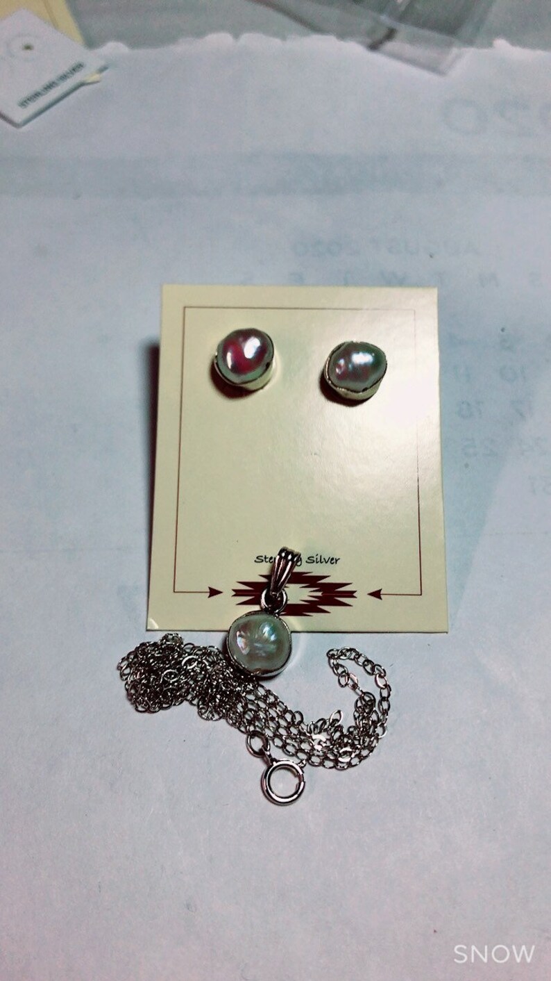 May include: A set of pearl earrings and a pearl pendant necklace with a sterling silver chain. The earrings and pendant are on a white card with the words "Sterling Silver" printed on it.