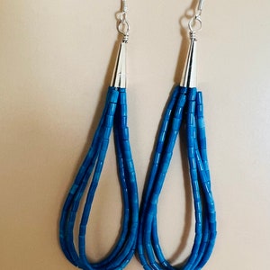 May include: A pair of long, dangling earrings with blue beads and silver hooks.