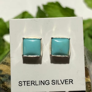 May include: A pair of sterling silver earrings with square turquoise stones.