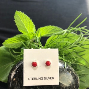 May include: A pair of red gemstone stud earrings on a white card with the text "STERLING SILVER".