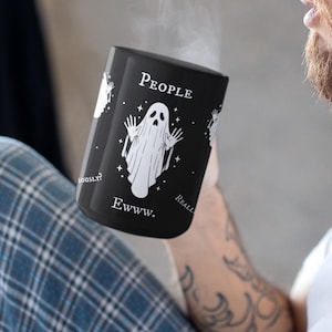 May include: A black ceramic mug featuring a white graphic of a ghost with raised hands, surrounded by small stars. The text "People" is printed above the ghost, and "Ewww." is printed below it, with "Seriously?" and "Really?" on the sides.