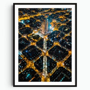 May include: An aerial night view of a city grid featuring the Sagrada Familia illuminated in the center. The urban landscape displays a pattern of square city blocks with glowing yellow street lights and dark building rooftops in a high contrast.