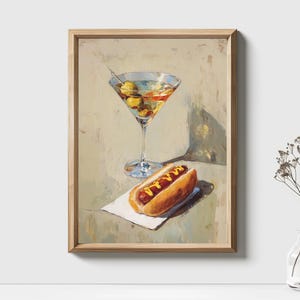 May include: A framed painting depicts a martini with olives and a hot dog with mustard on a napkin. The painting has a light color palette with a wooden frame. The martini glass is tall and slender, and the hot dog is in a bun.