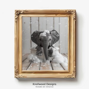 Könnte beinhalten: Ein Schwarzweißfoto eines Babyelefanten, das in einer mit Blasen gefüllten Wanne ein Bad nimmt. Der Elefant sitzt in der Wanne, sein Rüssel ist erhoben und seine Ohren schlagen. Das Foto ist in einem goldenen Rahmen gerahmt.