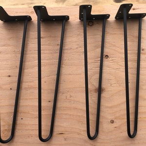 May include: Four black metal hairpin legs for furniture. The legs are about 12 inches tall and have a simple, modern design.