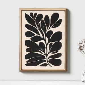 Op de afbeelding: Zwart-witte abstracte kunstprint van een gestileerde plant met grote bladeren. De print is ingelijst in een licht houten lijst.